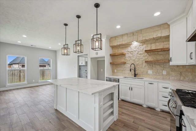 kitchen with backsplash, open shelves, a kitchen island, stainless steel appliances, and a sink