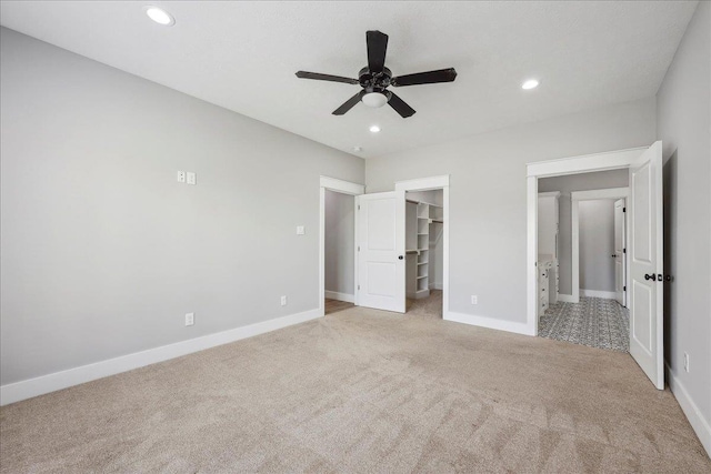 unfurnished bedroom with recessed lighting, a walk in closet, baseboards, and carpet flooring