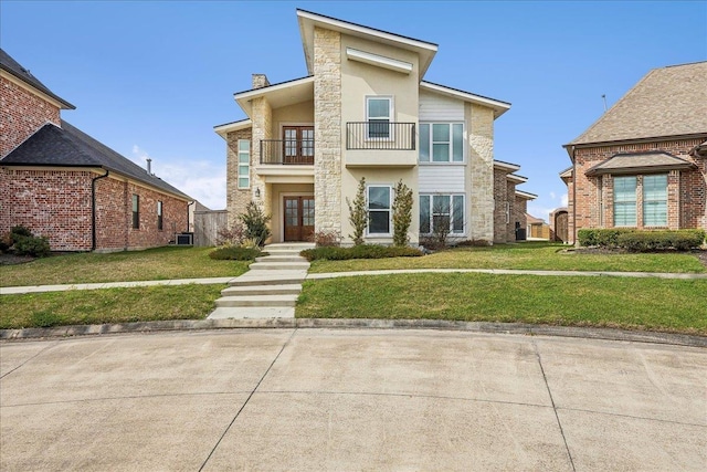 view of front of property featuring stucco siding, a balcony, a front yard, and french doors