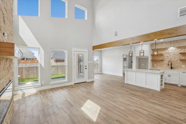 unfurnished living room featuring visible vents, baseboards, and light wood-style flooring