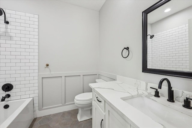 bathroom with vanity, shower / bathing tub combination, wainscoting, tile patterned floors, and toilet