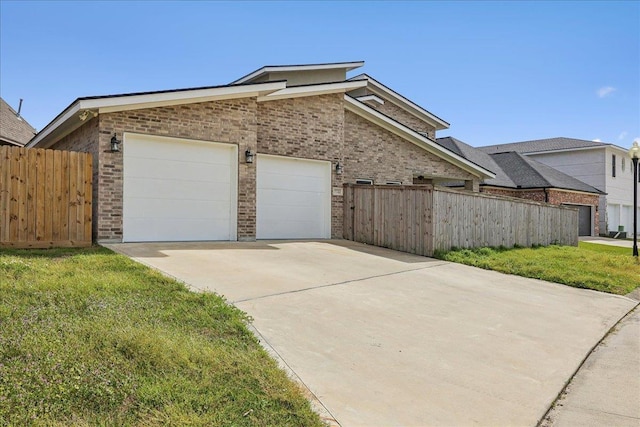 view of side of home with a lawn, fence, concrete driveway, an attached garage, and brick siding