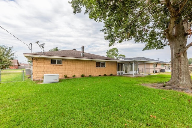 rear view of property featuring a patio area, a sunroom, and a yard