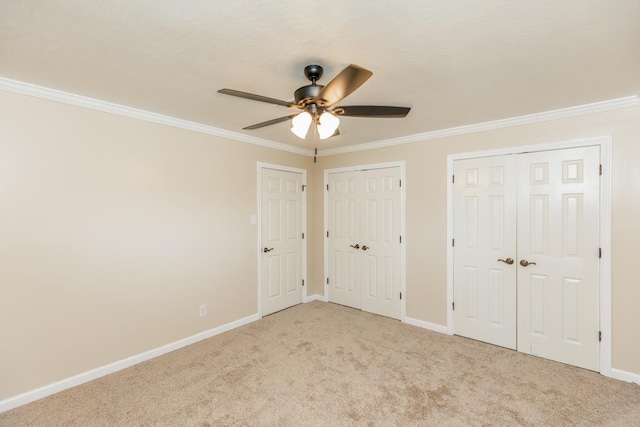 unfurnished bedroom featuring light carpet, two closets, ceiling fan, and ornamental molding