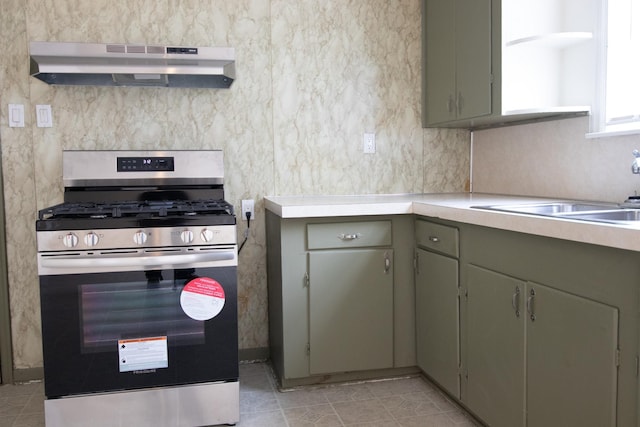 kitchen featuring gas stove, sink, range hood, and green cabinetry