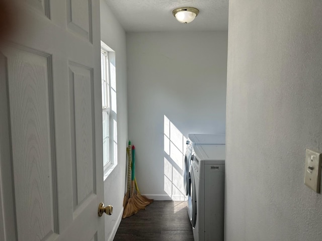 clothes washing area featuring dark wood-type flooring, washer and clothes dryer, and a healthy amount of sunlight