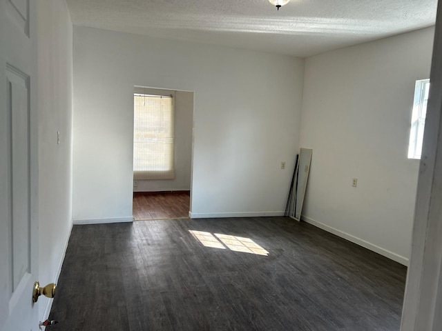 empty room with a textured ceiling and dark hardwood / wood-style flooring