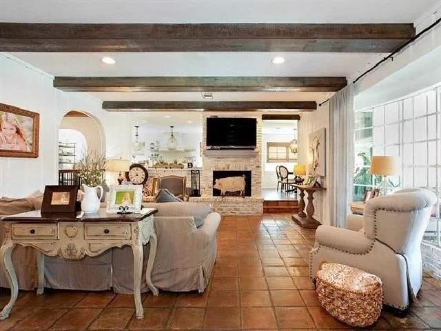 tiled living room featuring a large fireplace and beamed ceiling