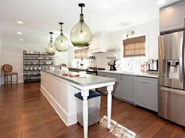 kitchen with gray cabinetry, pendant lighting, stainless steel appliances, and dark hardwood / wood-style floors