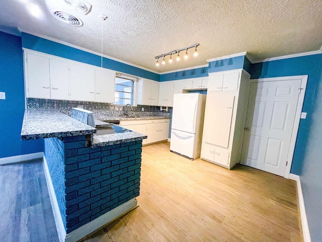 kitchen with white refrigerator, sink, white cabinetry, light hardwood / wood-style floors, and kitchen peninsula