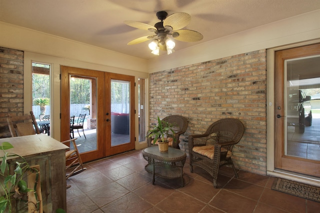 interior space with a sunroom, brick wall, ceiling fan, and french doors