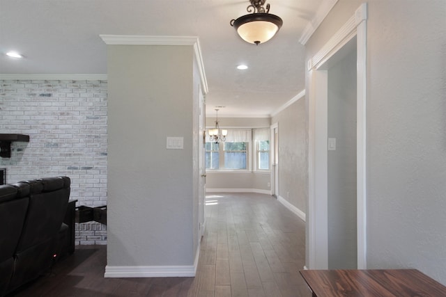 corridor with dark wood finished floors, crown molding, recessed lighting, an inviting chandelier, and baseboards