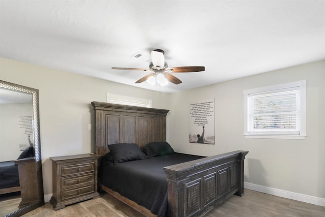 bedroom featuring light wood-style flooring, visible vents, baseboards, and ceiling fan