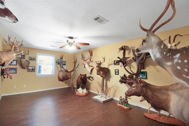 workout room with a ceiling fan, visible vents, a textured ceiling, and wood finished floors