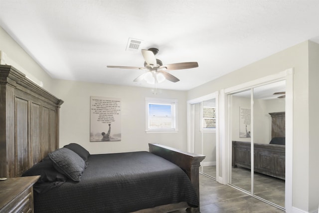 bedroom featuring dark wood finished floors, ceiling fan, baseboards, and two closets