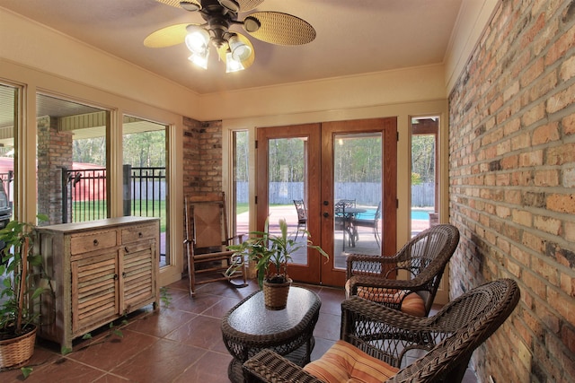 sitting room with dark tile patterned floors, brick wall, a ceiling fan, and french doors