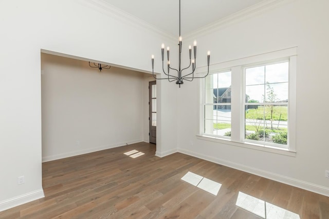 unfurnished dining area with hardwood / wood-style flooring, crown molding, and an inviting chandelier