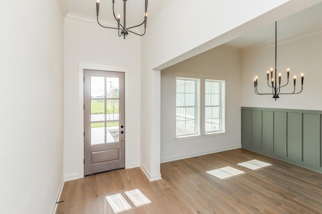 foyer entrance featuring ornamental molding, an inviting chandelier, and light hardwood / wood-style flooring