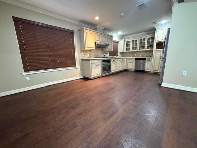 6845 Hialeah Dr, Beaumont, TX 77706 - kitchen with appliances with stainless steel finishes, under cabinet range hood, crown molding, dark wood-type flooring, and decorative backsplash