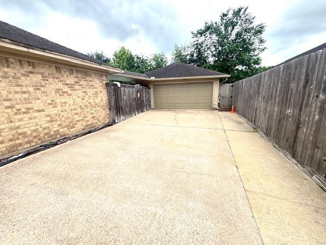 6845 Hialeah Dr, Beaumont, TX 77706 - view of side of home with an attached garage, concrete driveway, and brick siding