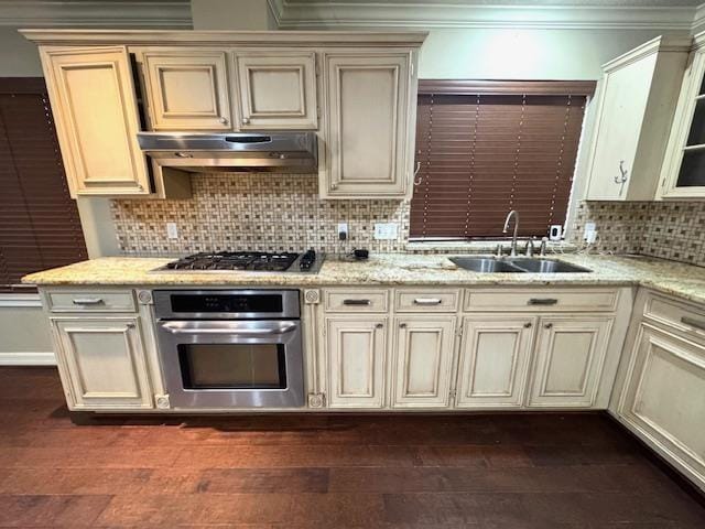 6845 Hialeah Dr, Beaumont, TX 77706 - kitchen with stainless steel appliances, cream cabinetry, range hood, a sink, and tasteful backsplash