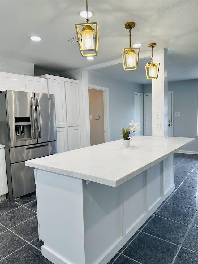 kitchen with hanging light fixtures, white cabinetry, and stainless steel fridge