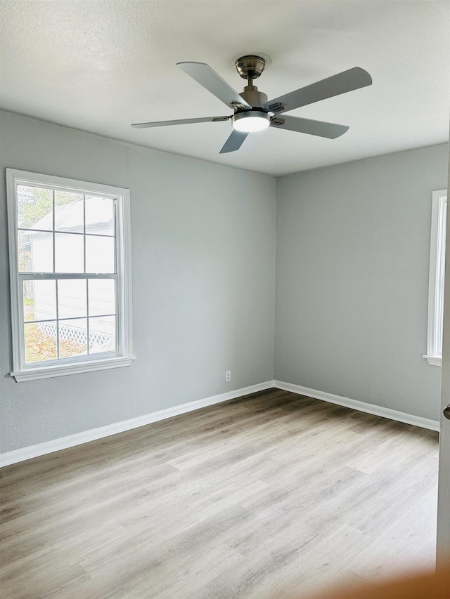 empty room with ceiling fan, a textured ceiling, and light hardwood / wood-style flooring