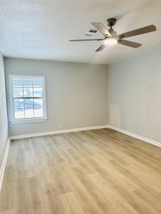 spare room featuring ceiling fan, light hardwood / wood-style flooring, and a textured ceiling