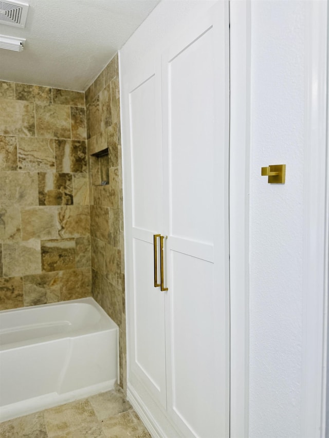 bathroom featuring tiled shower / bath combo, tile patterned floors, and a textured ceiling