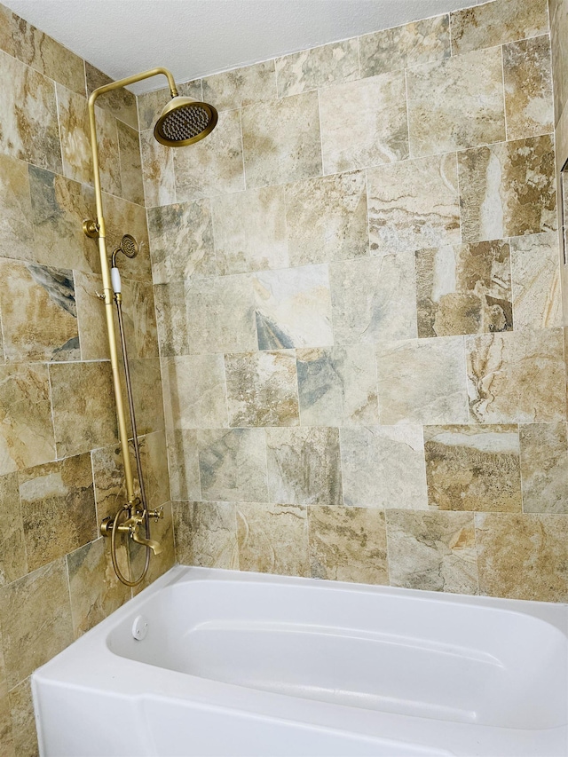 bathroom featuring tiled shower / bath and a textured ceiling