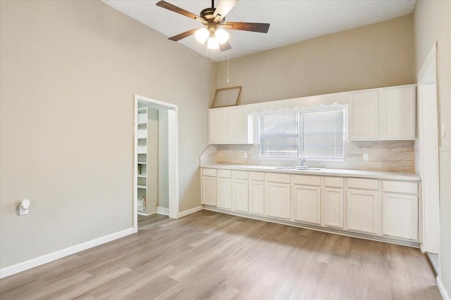 kitchen featuring light wood-type flooring, backsplash, white cabinetry, and sink