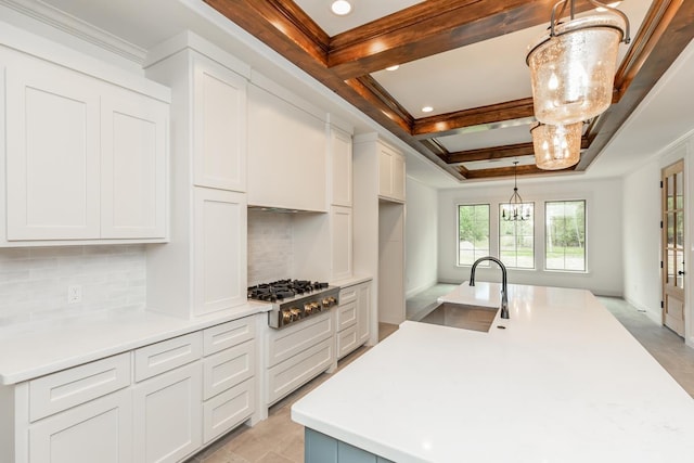 kitchen with white cabinetry, stainless steel gas stovetop, decorative light fixtures, and sink