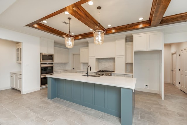 kitchen with sink, white cabinets, hanging light fixtures, stainless steel appliances, and a center island with sink