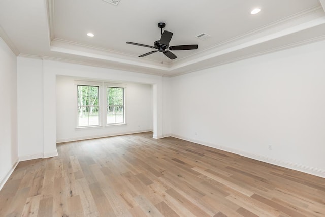 spare room with ceiling fan, ornamental molding, a raised ceiling, and light hardwood / wood-style flooring