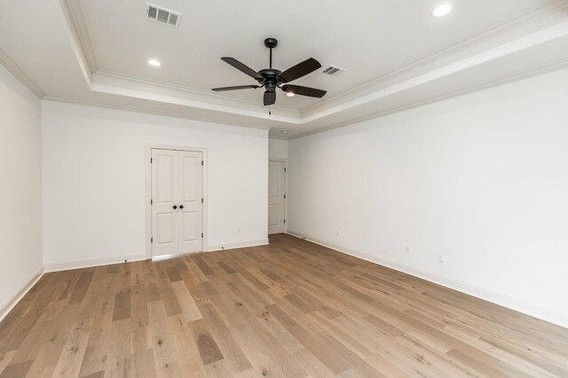 spare room with ornamental molding, ceiling fan, light hardwood / wood-style floors, and a tray ceiling