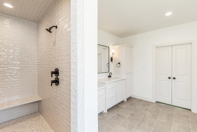 bathroom with ornamental molding, tiled shower, and vanity