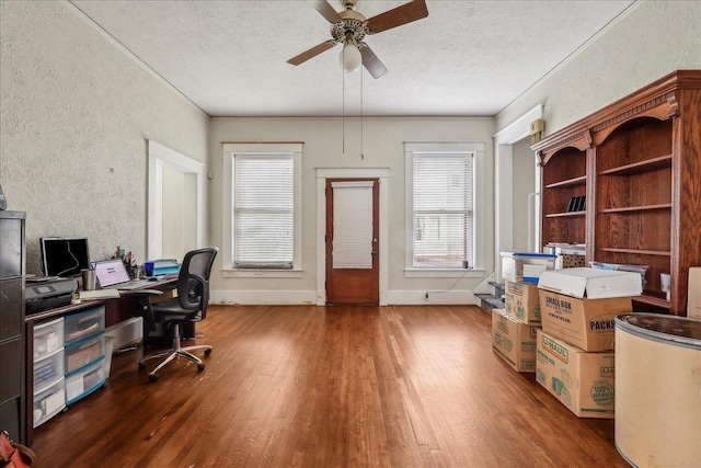 office area with a ceiling fan, a textured wall, wood finished floors, and a textured ceiling