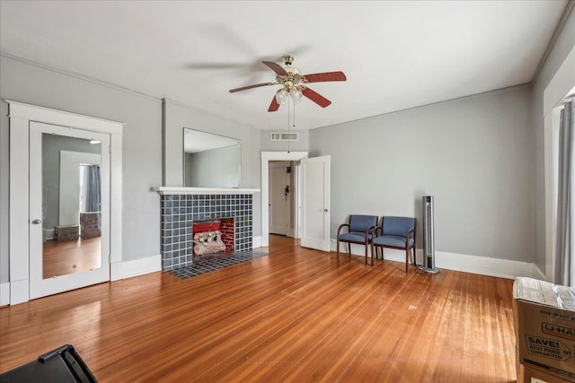 living room featuring a ceiling fan, baseboards, visible vents, and wood finished floors