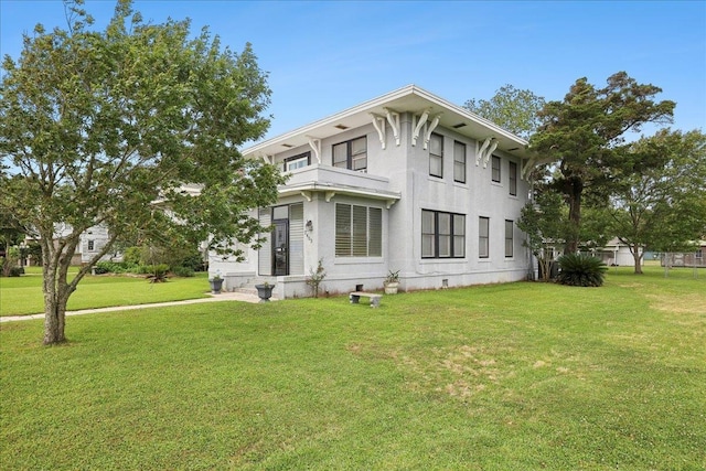 view of front of home with stucco siding, a front lawn, and a balcony