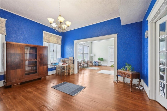 interior space with a textured ceiling, a textured wall, wood finished floors, and a chandelier