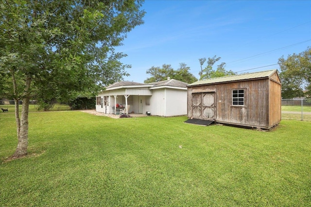 back of house with an outdoor structure, a storage shed, fence, and a yard