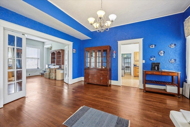 dining area featuring baseboards, an inviting chandelier, a textured wall, and wood finished floors