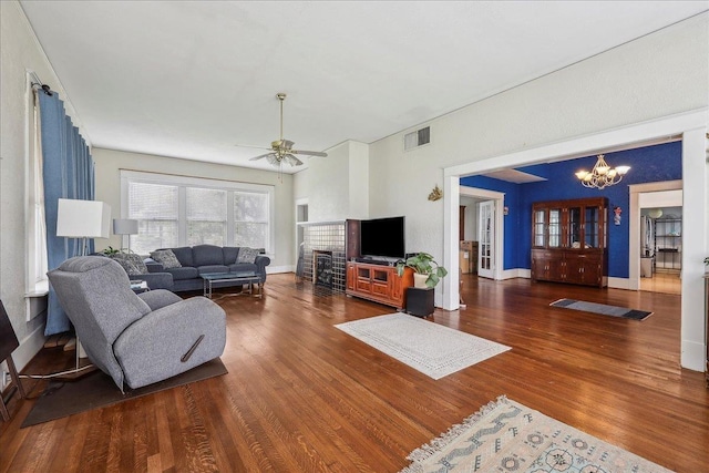 living room with baseboards, ceiling fan with notable chandelier, wood finished floors, and visible vents