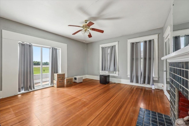 unfurnished living room with a ceiling fan, baseboards, and hardwood / wood-style flooring