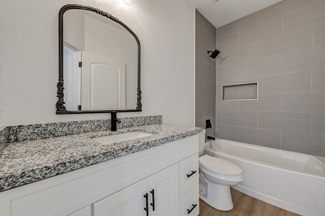 full bathroom with vanity, wood-type flooring, tiled shower / bath combo, and toilet