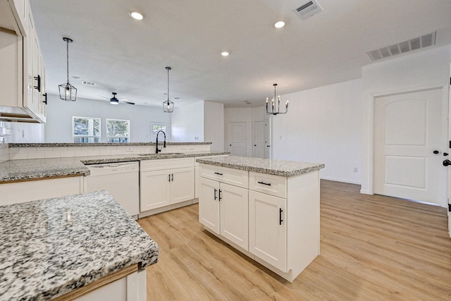 kitchen featuring ceiling fan with notable chandelier, white dishwasher, a kitchen island, and sink