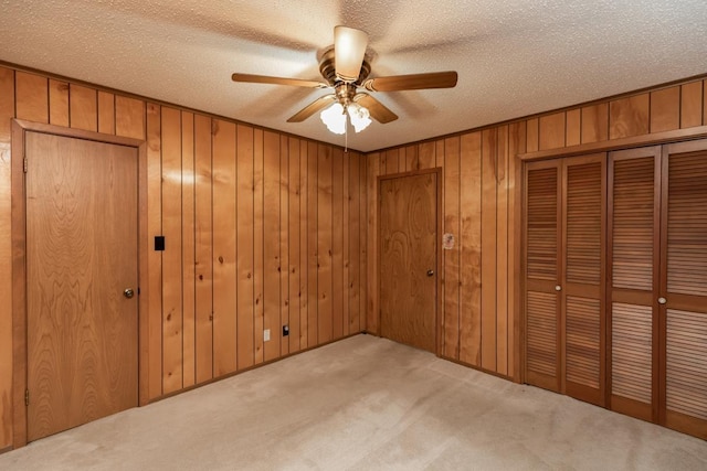 190 Magnolia Trl, Lumberton, TX 77657 - unfurnished bedroom featuring carpet flooring, a textured ceiling, wood walls, and a ceiling fan