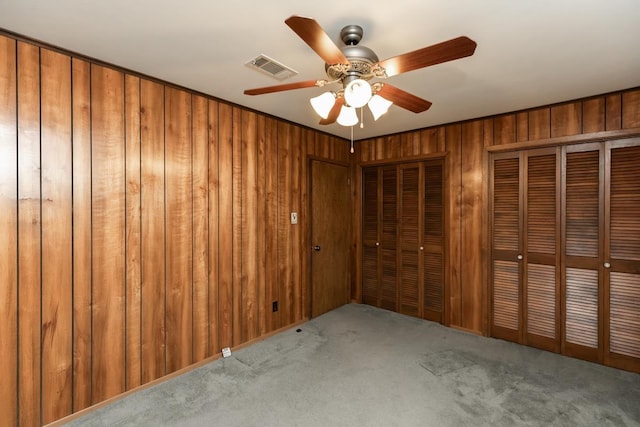 190 Magnolia Trl, Lumberton, TX 77657 - unfurnished bedroom featuring two closets, carpet flooring, wooden walls, and a ceiling fan