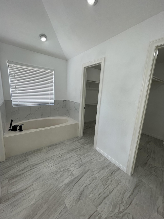 bathroom with lofted ceiling and a tub to relax in