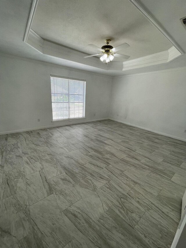 spare room with ceiling fan and a raised ceiling